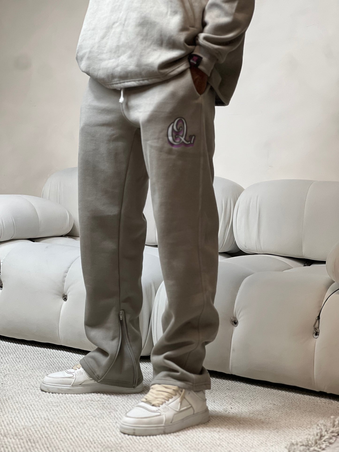 "Grey relaxed-fit lounge pants made from soft fleece fabric, featuring a subtle signature logo on the hip. Designed for comfort with an elastic waistband and adjustable drawstring for a customizable fit. Ideal for lounging or casual wear, offering a cozy and stylish look."



